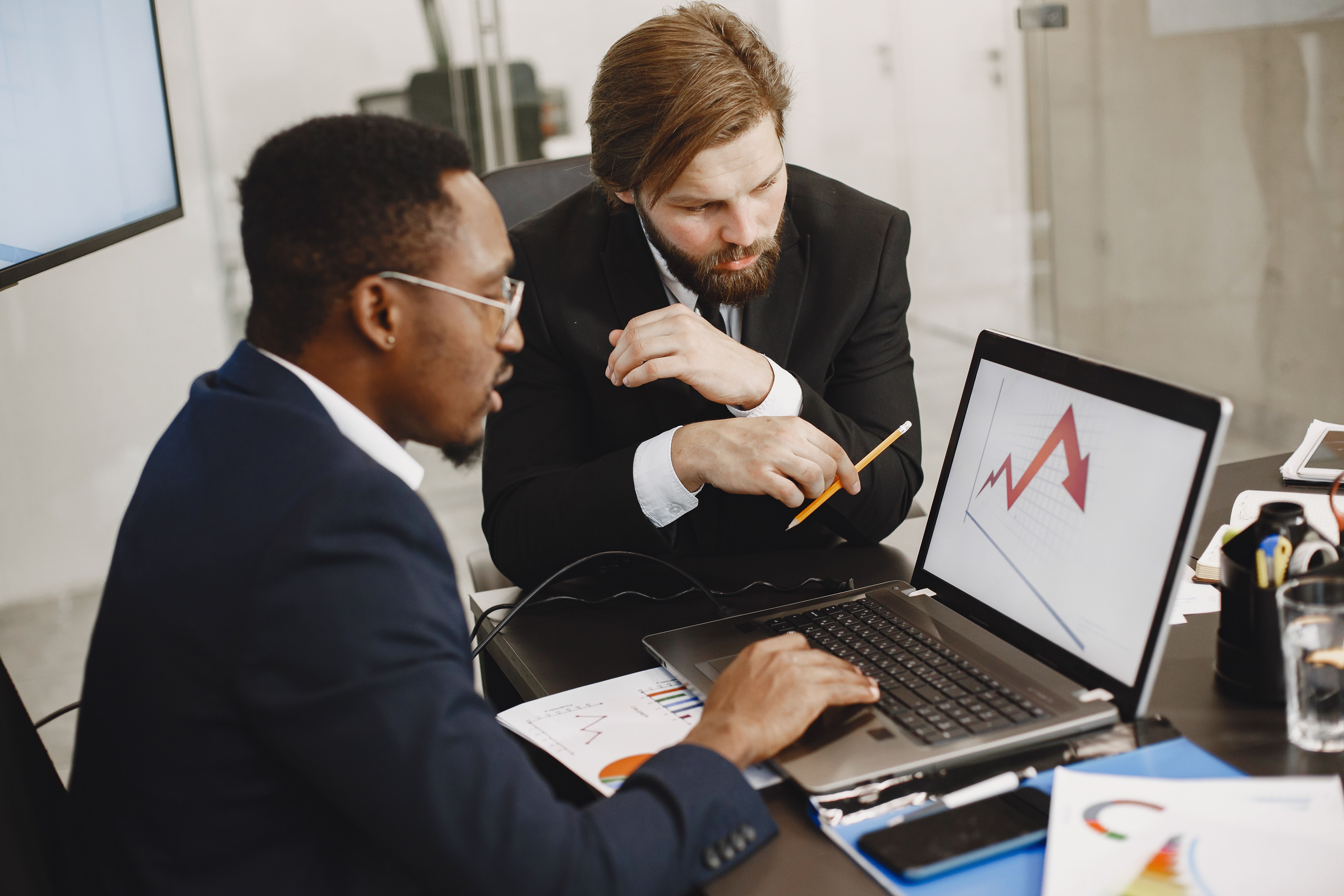 Two business professionals discussing marketing data on a laptop, representing hiring an SEO expert