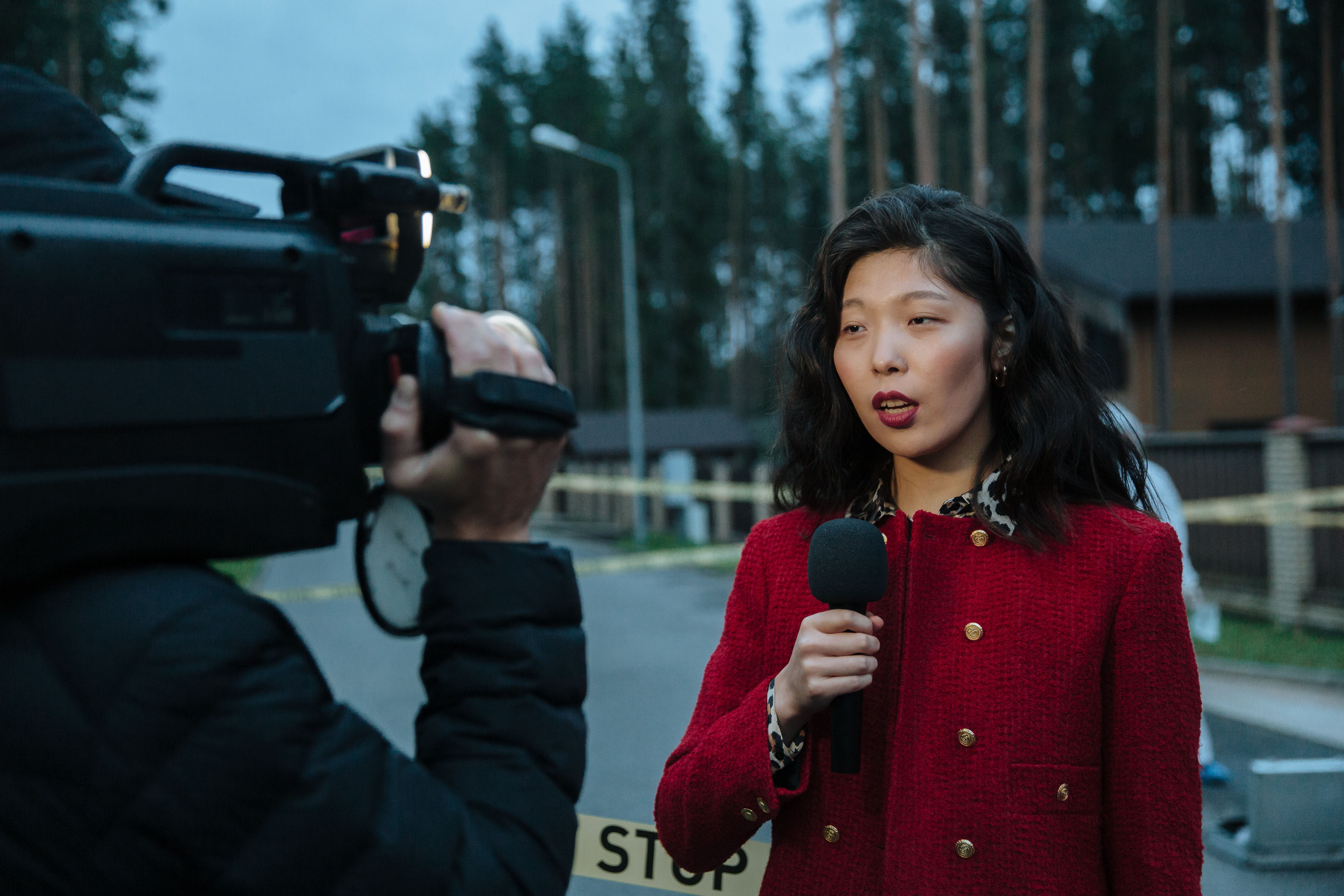 Female journalist reporting live with a camera and microphone in the field