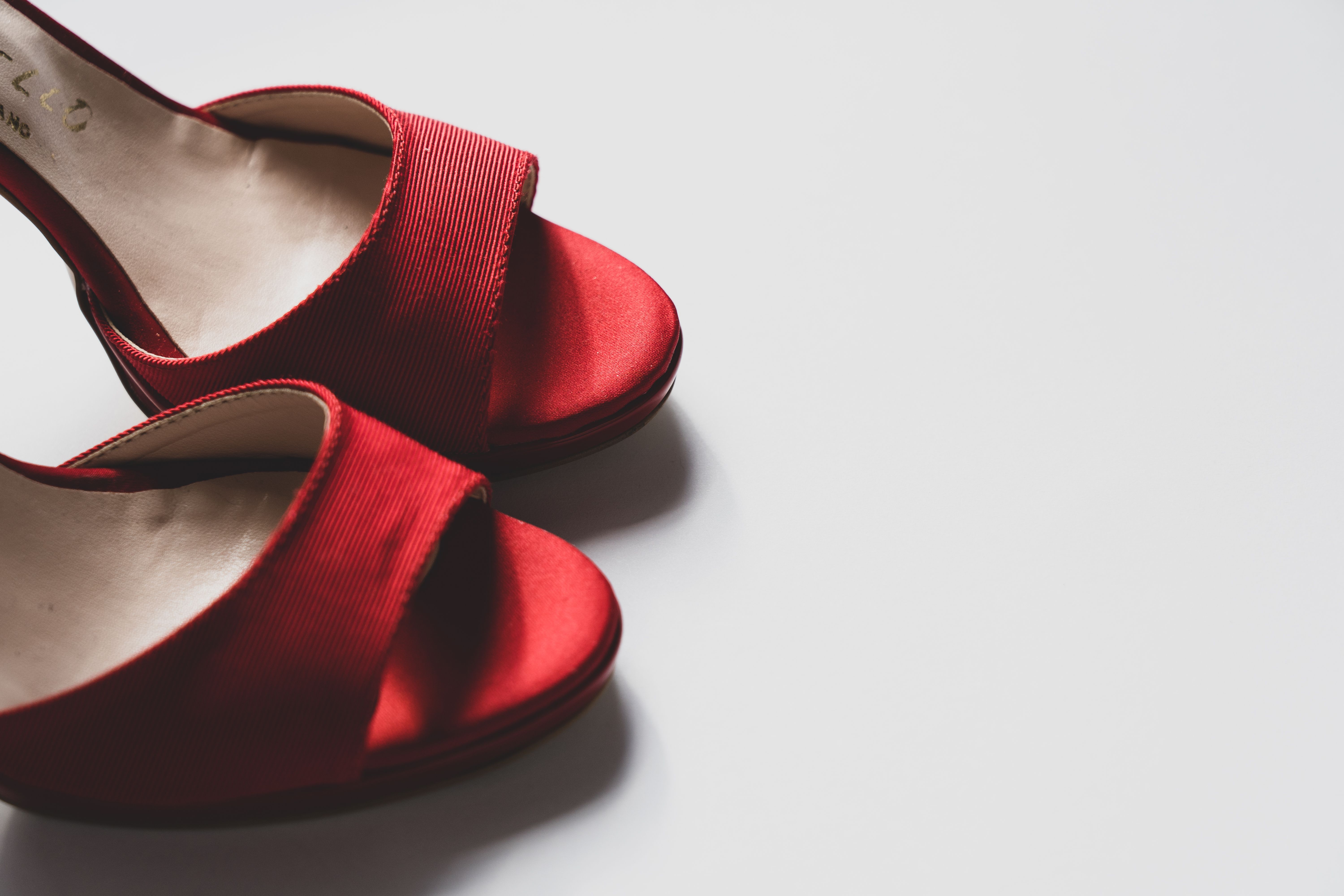 Pair of red high heels on a white surface representing domination and control