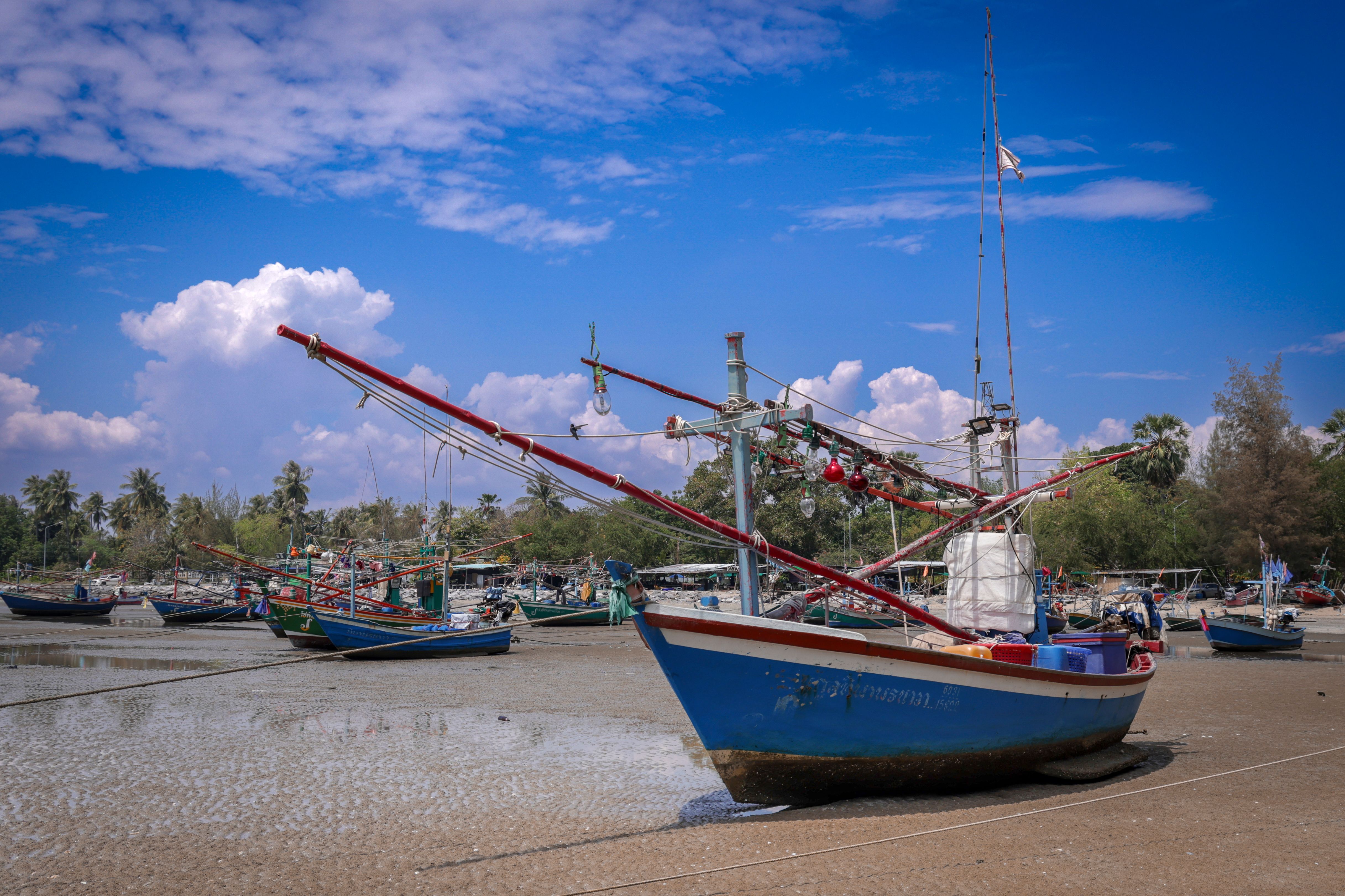 Colorful fishing boats resting on the sandy shore at low tide in Thailand