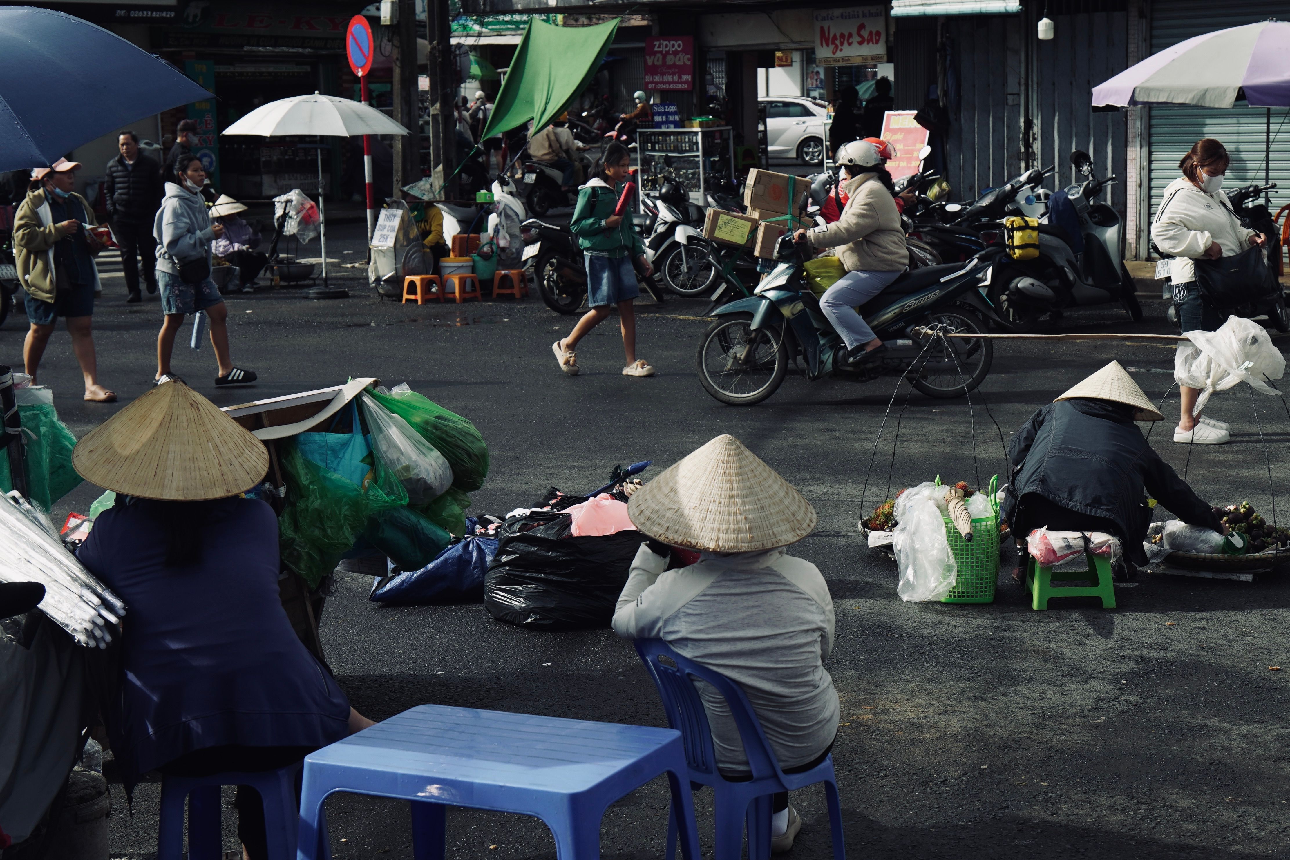 Vibrant Vietnamese street market bustling with locals in traditional hats